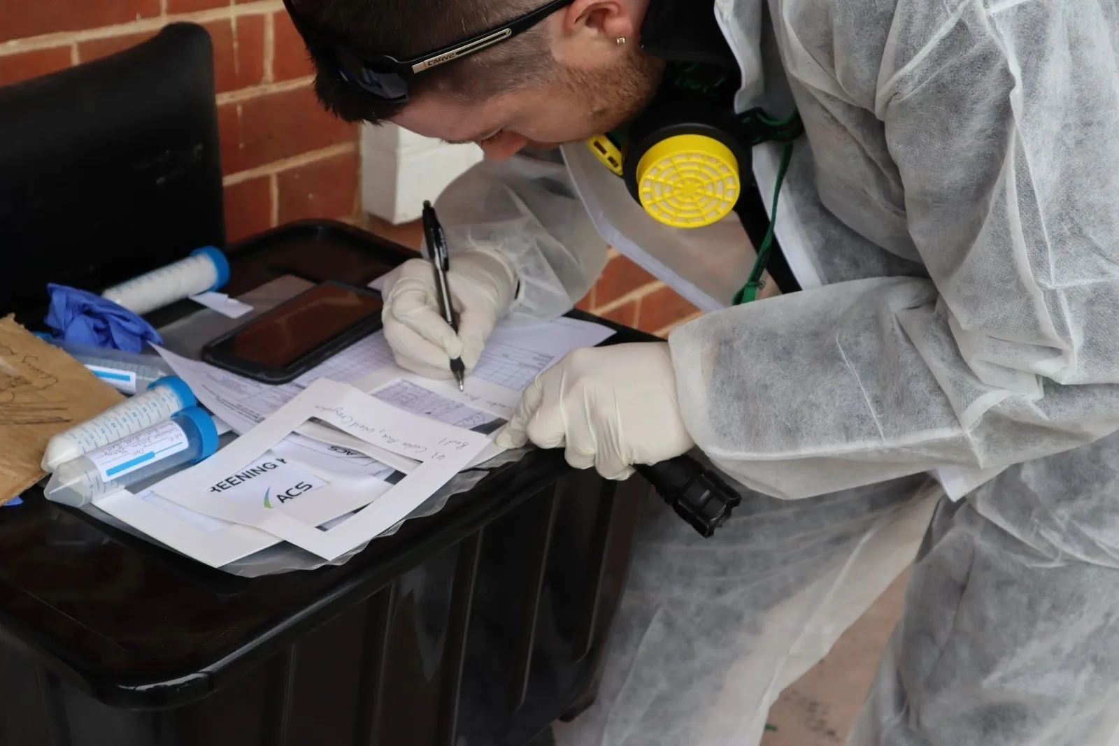 Inspector in protective gear completing an on-site inspection report